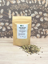 PMS Relief herbal tea package with loose tea on a wooden surface and floral background